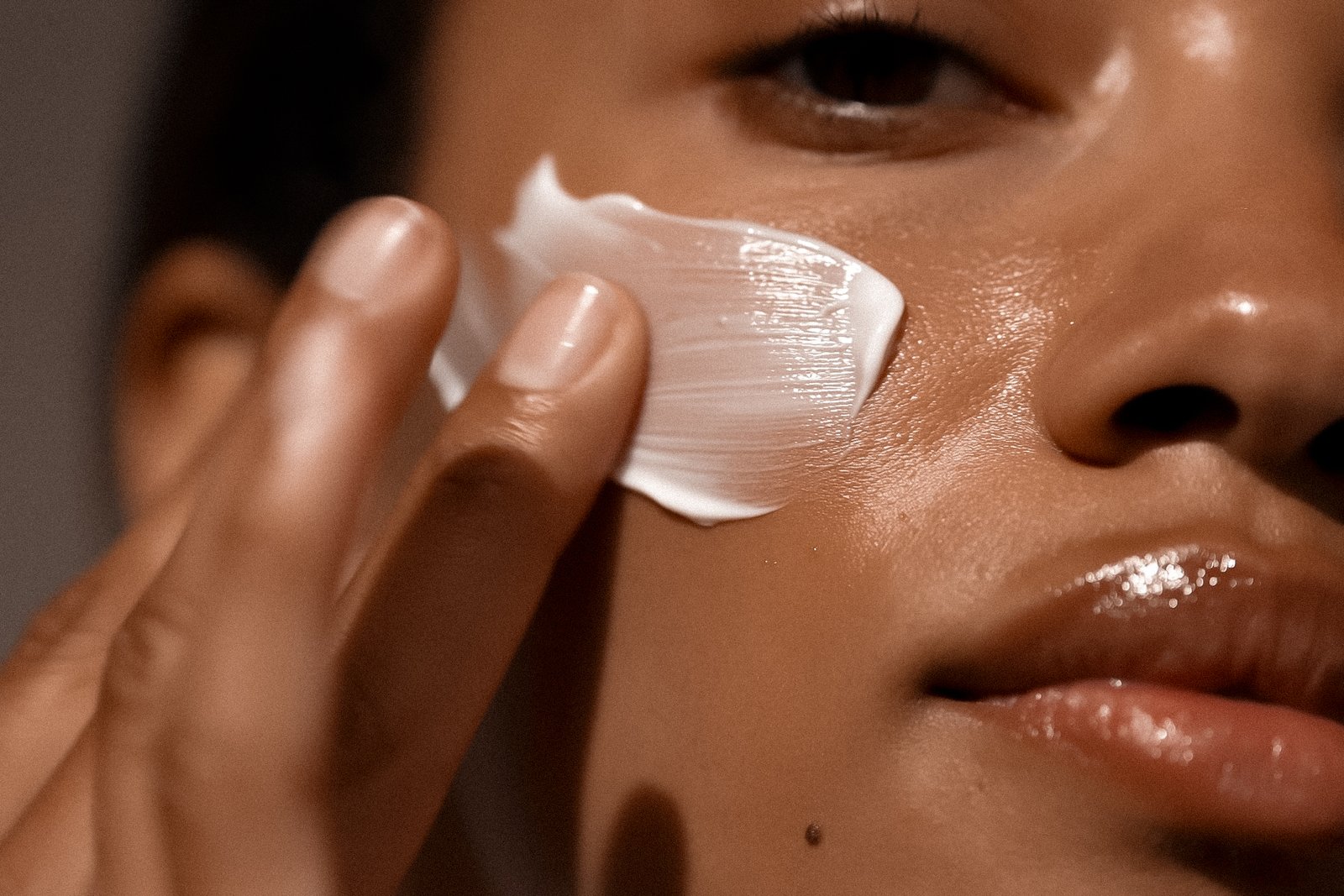 Woman applying skincare cream to her cheek — Skin! Medical Aesthetics, Denver